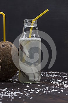 Vegan beverage from coconuts in bottle. Coconuts and coconut flakes