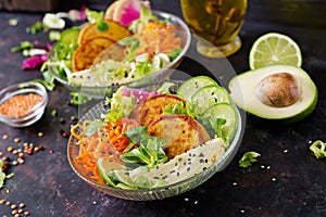 Vegan buddha bowl dinner food table. Healthy vegan lunch bowl. Fritter with lentils and radish, avocado, carrot salad.