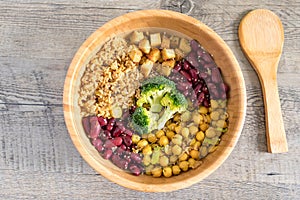 Vegan buddha bowl with stir fry tofu, brown rice, broccoli, red kidney beans, cooked chickpeas, seeds and vegetables.