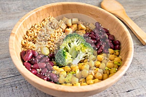 Vegan buddha bowl with stir fry tofu, brown rice, broccoli, red kidney beans, cooked chickpeas, seeds and vegetables.