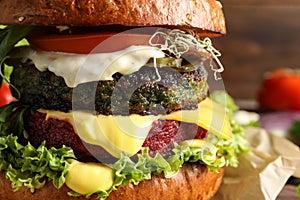 Vegan burger with beet and falafel patties on blurred background
