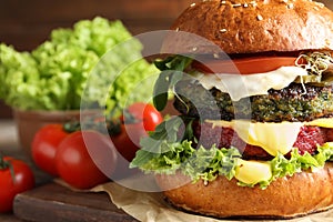 Vegan burger with beet and falafel patties on table against blurred background