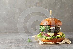 Vegan burger with beet and falafel patties on table against grey background.