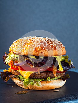 Vegan burger consisting on a slate plate. gray background. Vertical orientation.