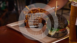 Vegan burger with French fries. Burger with plant based meat cheese. Lunch is on the table. Close-up of a hamburger with cheese on