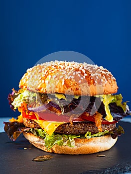 Vegan burger on a slate plate. blue background. Vertical.