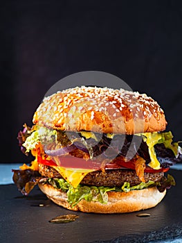 Vegan burger on a slate plate. dark background. Vertical orientation.