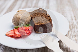 Vegan cake, vegan ice cream and strawberries on a wooden table