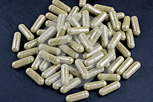 Vegan capsules dietary supplement on a black background top view.