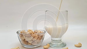 Vegan cashew milk pouring in a glass, closeup view, Healthy non dairy milk alternative.