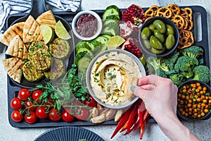 Vegan charcuterie board. Hummus bowl with vegetables, fried chickpeas, olives, falafel and pita bread