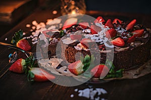 Vegan chocolate cake with strawberries, cocnut shovel and raspberry seeds, served on a paper serviette