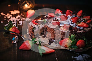 Vegan chocolate cake with strawberries, cocnut shovel and raspberry seeds, served on a paper serviette