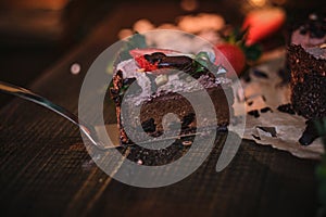 Vegan chocolate cake with strawberries, cocnut shovel and raspberry seeds, served on a paper serviette