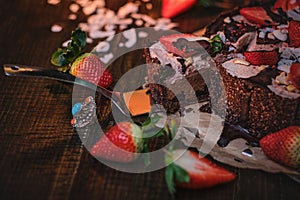 Vegan chocolate cake with strawberries, cocnut shovel and raspberry seeds, served on a paper serviette