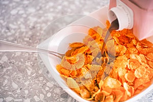 Vegan chocolate milk pouring into bowl with gluten free corn flakes