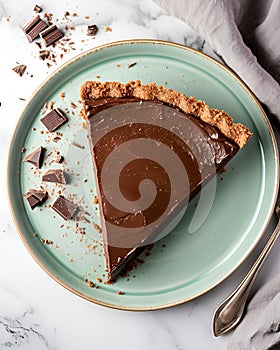vegan chocolate pie on a light green plate, placed on a marble table, around it there are pieces of chocolate.