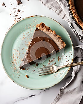 vegan chocolate pie on a light green plate, placed on a marble table, around it there are pieces of chocolate.