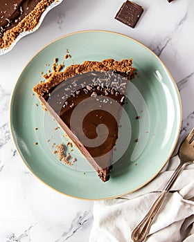 vegan chocolate pie on a light green plate, placed on a marble table, around it there are pieces of chocolate.