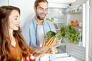 Vegan couple with fresh vegatables at the kitchen