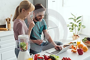 vegan couple using laptop together in kitchen