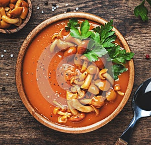 Vegan creamy pumpkin soup with mushrooms, hot pepper and parsley. Winter or autumn healthy vegetarian slow food. Wooden bowl on