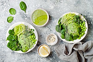 Vegan, detox Buddha bowl with avocado, spinach, micro greens, edamame beans, zucchini noodles and herb green dressing photo