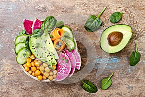 Vegan, detox Buddha bowl recipe with avocado, carrots, spinach, chickpeas and radishes. Top view, flat lay, copy space.