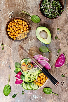 Vegan, detox Buddha bowl recipe with avocado, carrots, spinach, chickpeas and radishes. Top view, flat lay, copy space.