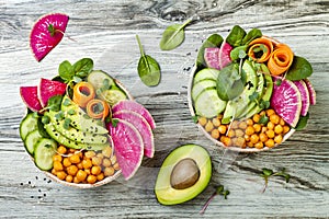 Vegan, detox Buddha bowl recipe with avocado, carrots, spinach, chickpeas and radishes. Top view, flat lay, copy space.