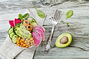 Vegan, detox Buddha bowl recipe with avocado, carrots, spinach, chickpeas and radishes. Top view, flat lay, copy space.