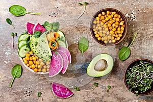 Vegan, detox Buddha bowl recipe with avocado, carrots, spinach, chickpeas and radishes. Top view, flat lay, copy space. photo