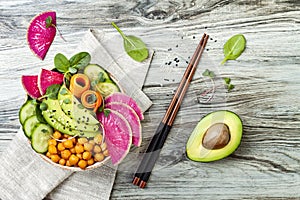 Vegan, detox Buddha bowl recipe with avocado, carrots, spinach, chickpeas and radishes. Top view, flat lay, copy space.