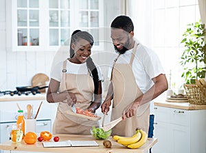 Vegan Diet. Happy young black couple cooking vegetable salad together in kitchen