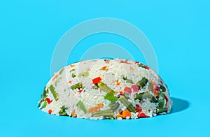 Vegan dish, white rice with a mix of vegetables isolated on a blue background