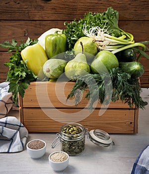Vegan food. Fresh green hypoallergenic vegetables for detox in wooden box and the seeds. Selective focus