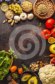 Vegan food ingredients on a dark background. Vegetables, fruits, cereals, nuts, beans top view.