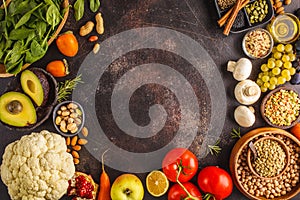 Vegan food ingredients on a dark background. Vegetables, fruits, cereals, nuts, beans top view.