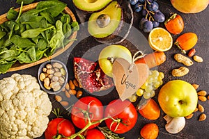 Vegan food ingredients on a dark background. Vegetables, fruits, cereals, nuts, beans top view.