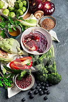 Vegan food. Pepper, broccoli, cabbage, garlic, mushrooms, pomegranate on a dark background