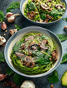 Vegan garlic mushroom pasta with spinach and avocado pesto drizzled with sesame seeds and roasted pine nuts