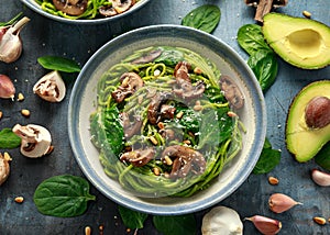 Vegan garlic mushroom pasta with spinach and avocado pesto drizzled with sesame seeds and roasted pine nuts