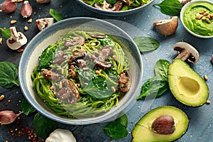 Vegan garlic mushroom pasta with spinach and avocado pesto drizzled with sesame seeds and roasted pine nuts