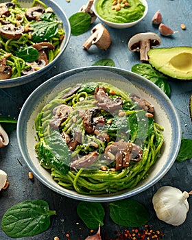 Vegan garlic mushroom pasta with spinach and avocado pesto drizzled with sesame seeds and roasted pine nuts