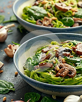 Vegan garlic mushroom pasta with spinach and avocado pesto drizzled with sesame seeds and roasted pine nuts