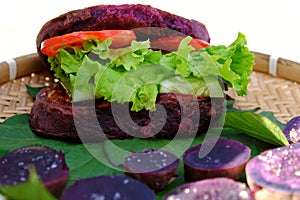 Vegan hamburger from violet sweet potato with tomato, salad