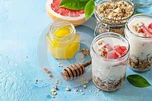 Vegan healthy breakfast. Granola with greek yogurt, honey and grapefruit in a glass. Copy space