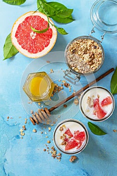 Vegan healthy breakfast. Granola with greek yogurt, honey and grapefruit in a glass. Top view flat lay background