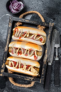 Vegan hot-dog with with assorted toppings and meatless Vegetarian sausage. Black background. Top view