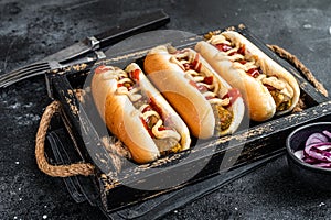 Vegan hot-dog with with assorted toppings and meatless Vegetarian sausage. Black background. Top view